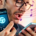 Person summt ins Smartphone zur Liedidentifikation.